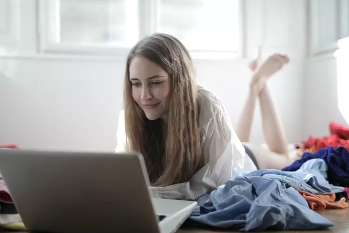 En kvinde ligger på sengen og kigger på computeren.